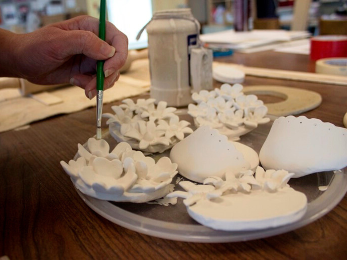 a hand paints a floral sculpture 